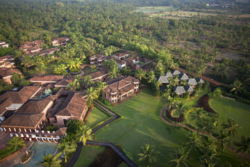 Bambolim, India - 16 November 2013: Aerial view of a luxury resort nestled amidst lush greenery, where terracotta roofs meet emerald lawns in a serene tropical escape.