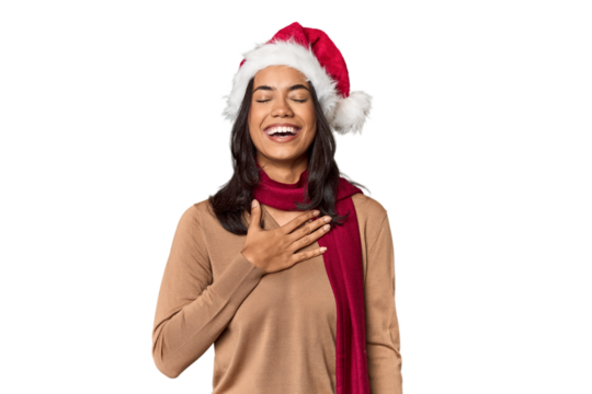 Filipino in Christmas attire and Santa hat laughs out loudly keeping hand on chest.