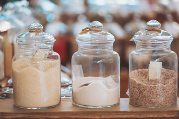 Jars filled with different types of sugar and salt showcase at a local market during the bustling afternoon hours