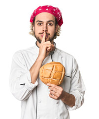 Young chef with artisan bread in studio keeping a secret or asking for silence.