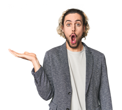 Young businessman in casual blazer impressed holding copy space on palm.