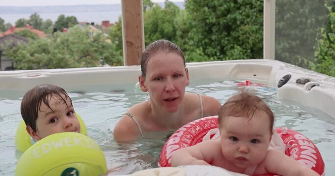 Mama und ihre beiden Kinder in einem Pool mit Seeblick