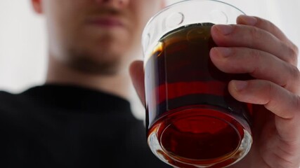 Tasting of expensive and rare alcohol.
Premium alcoholic drink in a glass.
A man drinks expensive whiskey or trom from a transparent glass.
Fortified alcoholic drink