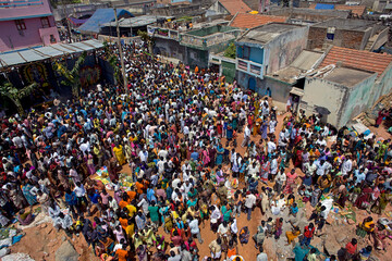 Puducherry, India - 28 February 2010: Aerial view of a vast crowd gathered, their vibrant clothes a stark contrast to the weathered buildings.