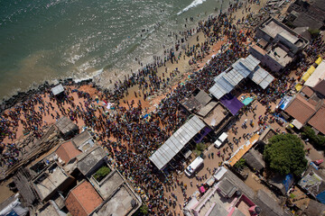 Puducherry, India - 28 February 2010: Aerial view of a vibrant gathering by the sea, where the sandy shore meets the bustling town, creating a mesmerizing blend of humanity and architecture.