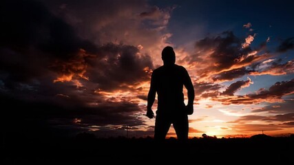 Silhouette of a person with arms raised against a vibrant, dramatic sunset sky filled with colorful clouds, conveying a sense of triumph and achievement.