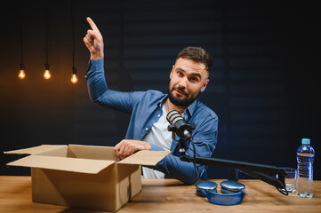 Video blogger unboxing product and pointing up while recording content in studio