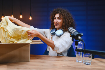 Influencer unboxing clothes in home studio recording video blog