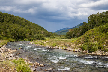 Summer mountain landscape. View of the river in the mountain valley. Travel, tourism and hiking on the Kamchatka Peninsula. Beautiful nature of Siberia and the Russian Far East. Kamchatka Krai, Russia