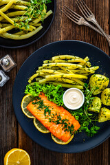 Fried salmon steak with yellow beans and boiled potatoes on wooden table	