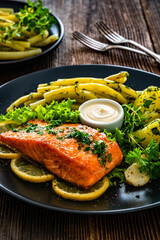 Fried salmon steak with yellow beans and boiled potatoes on wooden table	