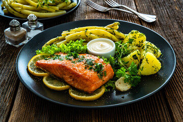 Fried salmon steak with yellow beans and boiled potatoes on wooden table	