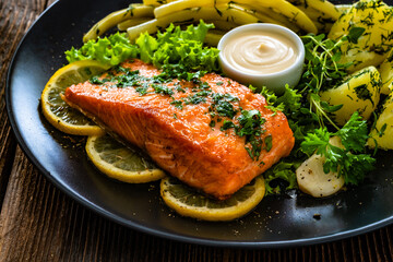 Fried salmon steak with yellow beans and boiled potatoes on wooden table	