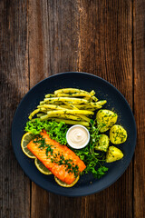 Fried salmon steak with yellow beans and boiled potatoes on wooden table	