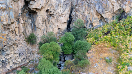 A high-angle view reveals a rocky ravine with a small stream running through it, surrounded by...