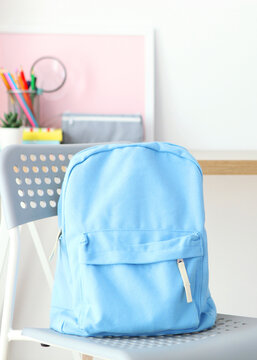 School backpack and stationery in a bright room.. Vertical photo format
