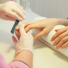 Closeup shot of a woman in a nail salon getting a manicure. Vertical photo format