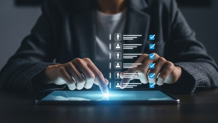 Man hands tapping glowing tablet with blue human icons and checklist icons in dim office, concept of applicant tracking and digital resume screening