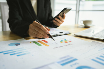 A businessman sits indoors at his office desk analyzing financial graphs on a laptop, planning investments, managing budget, taxes, and savings.