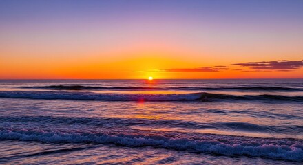 Fototapeta premium Beautiful sunrise over ocean waves. Colors of orange, pink, and purple paint the sky as the sun dips below the horizon, creating a stunning coastal scene. Gentle waves gently roll onto the shore