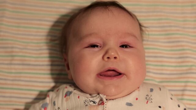 L&auml;chelndes Baby liegt auf dem R&uuml;cken und brabbelt