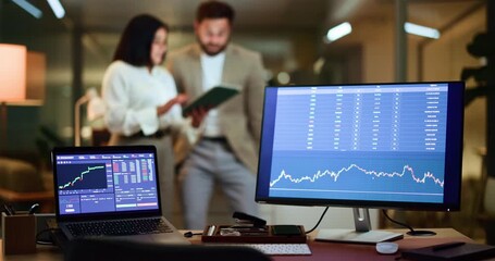 Business people, night and computer screen with stock market platform for trading in office. Businessman, woman or brokers with technology display or analytics for cryptocurrency, graph or chart - Powered by Adobe