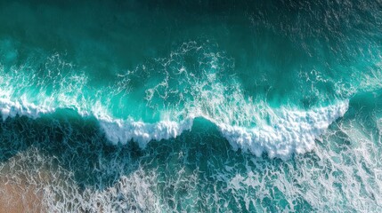 Obraz premium Aerial view of ocean waves crashing on sandy beach, vibrant turquoise water.