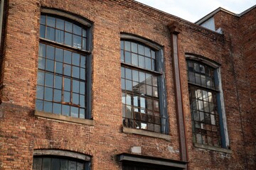 Obraz premium Weathered Brick Building Facade with Arched Windows and Metal Details