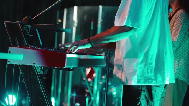 Keyboardist playing piano during worship service, turquoise stage lighting highlighting musical performance with spiritual energy