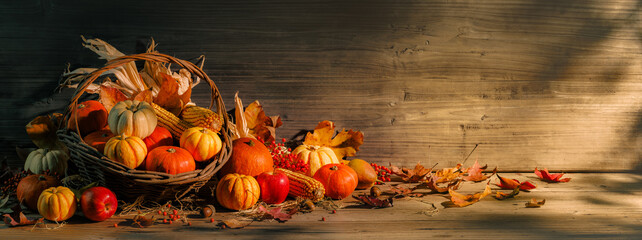 Festive basket overflowing with autumn harvest elements like pumpkins corn and leafs on a dark wooden background. Thanksgiving day.