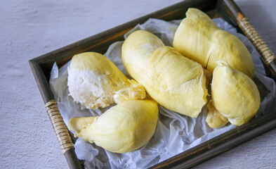 A yellow durian that has been peeled off to reveal the tasty yellow flesh of the durian. Durian fruit on wooden basket