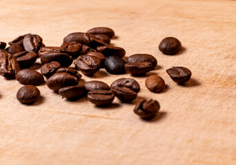 Roasted coffee beans scattered on wooden surface close up
