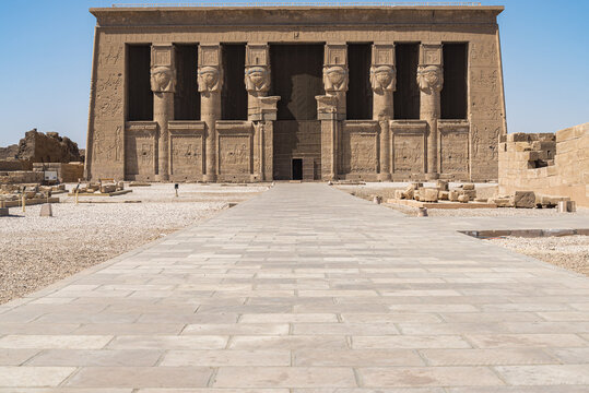 Frontal view of the facade of the temple of the city of "Dendera", Egypt, with several columns with the face of Goddess named "Hator". White floor in the foreground 