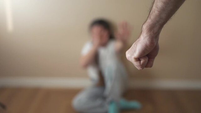 Person sitting on the floor with their hand up. A child is threatening to punch a girl with a fist. A girl is afraid of danger. An individual seated on the ground lifestyle with their hand raised.