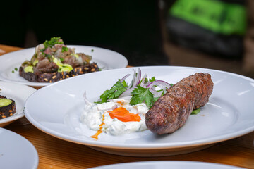 Grilled kofta kebabs with yogurt dip and parsley garnish. Traditional homemade lamb kafta or kofta kebab with sauce and yoghurt. Traditional Arabic and Turkish food. Halal food. 