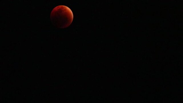 A beautiful rare blood moon on a dark night sky. Time lapse