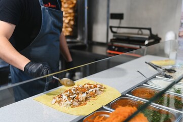 Chef adding sauce to shawarma using spoon in a street food kiosk