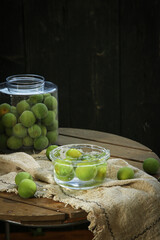 Fresh Green Plums in Glass Jars on Rustic Wooden Table for Preserving and Wine Making