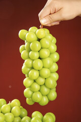 Fresh Green Grapes Bunch Held by Hand on Warm Wooden Background with Natural Lighting