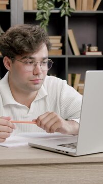Young boy stares at a computer screen and smiles discreetly. Handsome boy attends a refresher course and listens attentively to the information on the laptop