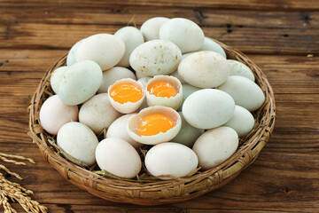 Fresh Raw Duck Eggs with Orange Yolks in Wicker Basket on Wooden Background