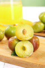 Fresh Sichuan Plums Cut in Half Showing Yellow Flesh on Wooden Board with Plum Juice