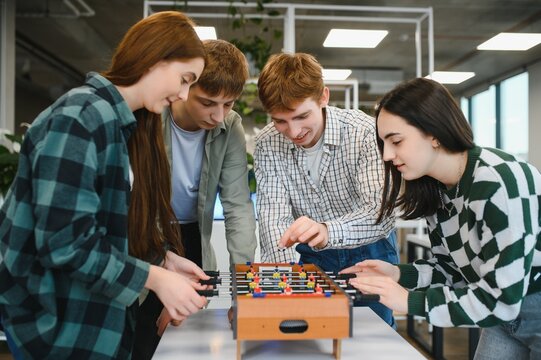 Startup employees playing table football in modern office