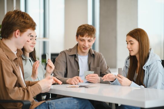 Group of young adults playing cards at home having fun