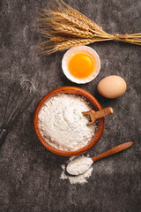 Fresh Wheat Flour Bowl with Eggs and Wheat Stalks - Baking Ingredients on Dark Stone Background