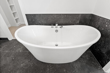 Large bathtub with a black tile floor