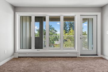 Large window in a room with a view of trees and a balcony