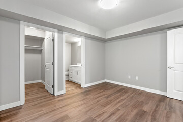 Large, empty room with a white door leading to a bathroom