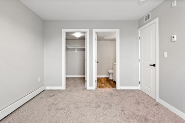 Large, empty room with a white door and a toilet