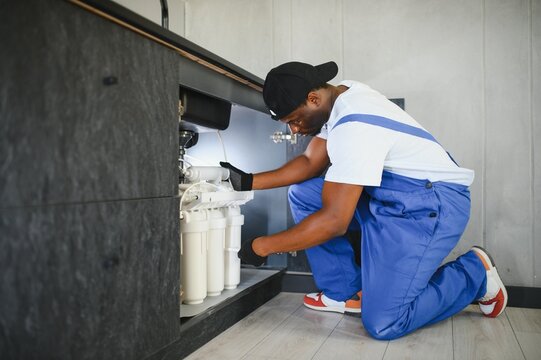 Plumber installs or change water filter. Replacement aqua filter. Repairman installing water filter cartridges in a kitchen. - Powered by Adobe